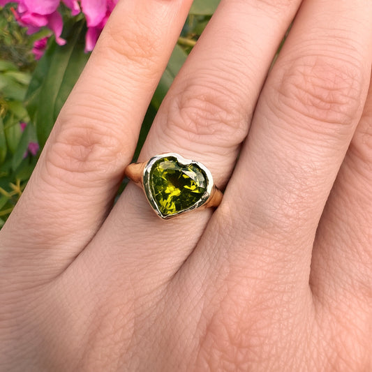 Unser Hey Amour Herz Ring ist aus 8 Karat Gelbold. Der Edelstein ein Peridot. Getragen ist er ein einzigartiger Ring. Handgefertigt in Berlin.